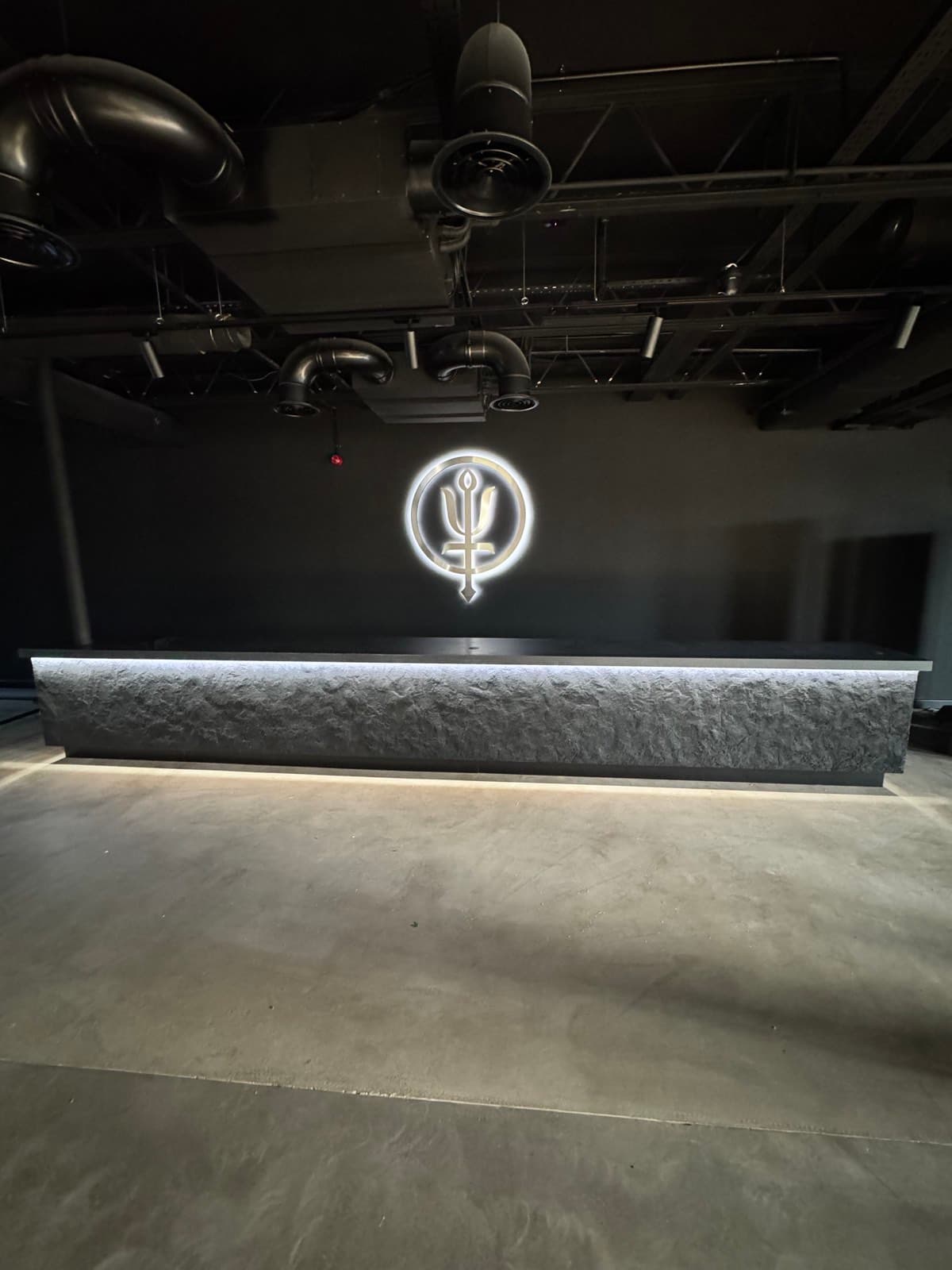 Textured stone-effect bar counter with LED edge lighting under an industrial ceiling